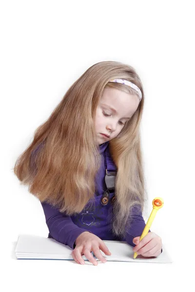 Tyttö kirjoittaa keltaisella kynällä — kuvapankkivalokuva