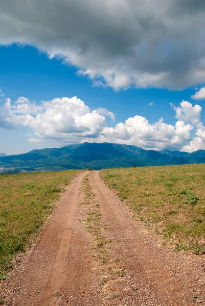 "Direct dirt road, on horizon mountain hills" — Stockfoto