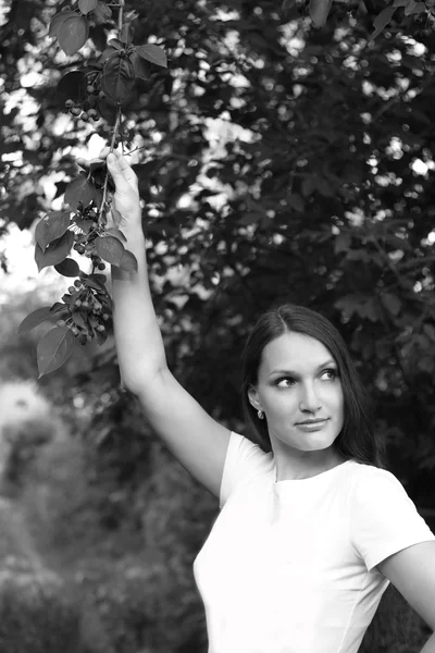 Длинноволосая девушка в белом жилете против листвы — стоковое фото