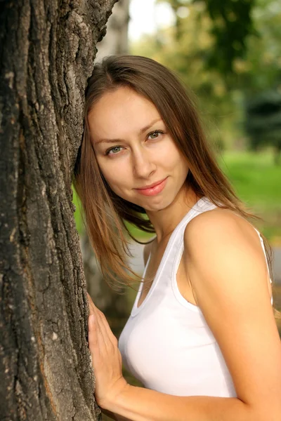 Krásná dívka v bílé vestě na starý strom — Stock fotografie