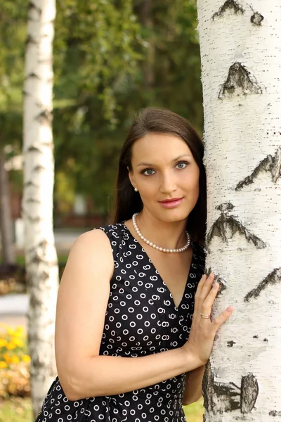 Krásná dívka v černých šatech na strom — Stock fotografie