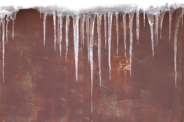 Stock image Icicles against a red-brown metal wall