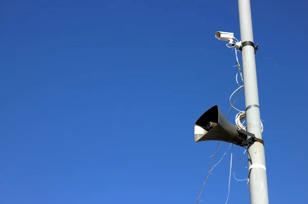 Camera en luidspreker op een kolom tegen de blauwe hemel — Stockfoto