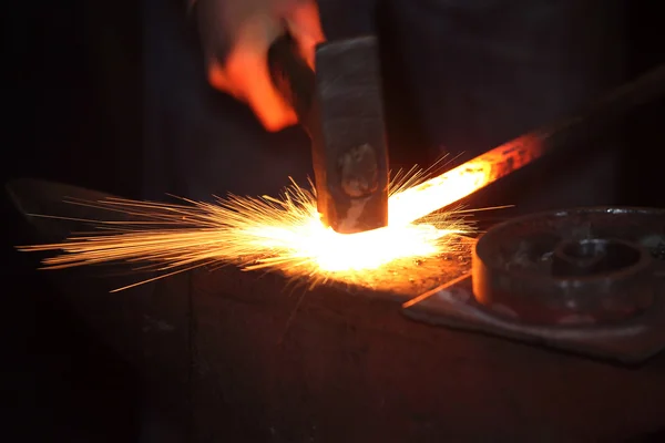 Руки коваля з молотком і сталевою паличкою Стокове Фото