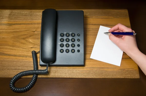 Landline telephone and human hand writing note — Stock Photo, Image