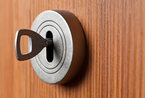 Серебряный ключ в коричневой двери — стоковое фото