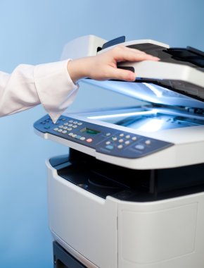 Woman's hand with working copier (focus on LCD screen) clipart