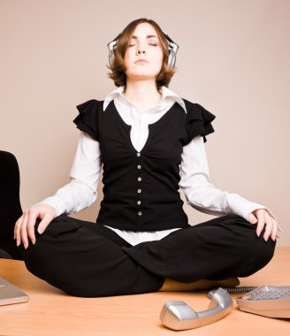 Young woman sitting in lotus pose with headphones clipart