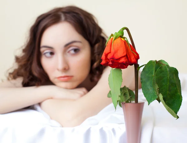 Woman in bed looking on the rose (focus on rose) — Stock Photo, Image