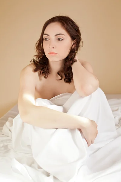 Όμορφη σέξι γυναίκα που κάθεται στο κρεβάτι για τα λευκά κλινοσκεπάσματα — Φωτογραφία Αρχείου