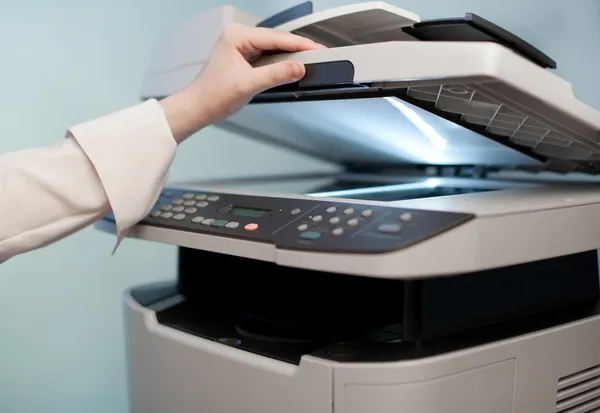 Woman's hand with working copier (focus on finger) — Stock Photo, Image