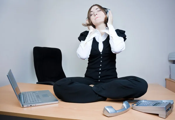 Donna d'affari seduta sulla scrivania ad ascoltare musica — Foto Stock