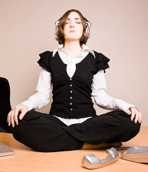 Mujer joven sentada en pose de loto con auriculares — Foto de Stock