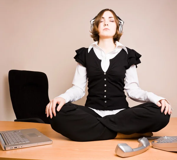 Young woman sitting in lotus pose with headphones — Stock Photo, Image