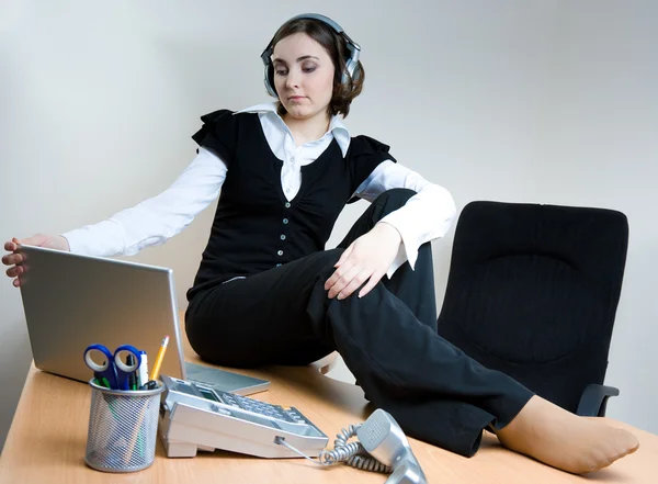Mujer joven sentada en el escritorio con auriculares — Foto de Stock