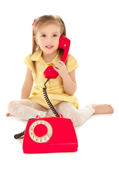 Katta oturan eski telefon ile küçük kız — Stok fotoğraf
