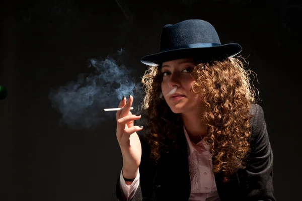 Mulher bonita de pé e fumar no fundo preto — Fotografia de Stock