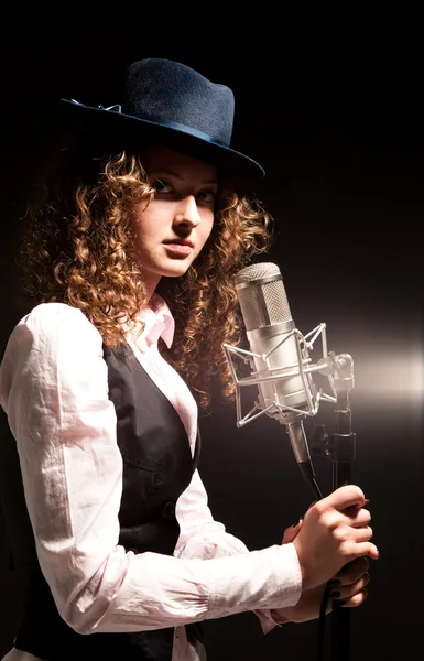 Piękna piosenkarka w kapeluszu z mikrofonem — Zdjęcie stockowe