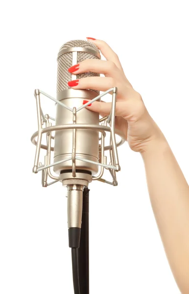 Kvinnans hand med röda naglar anläggning mikrofon — Stockfoto