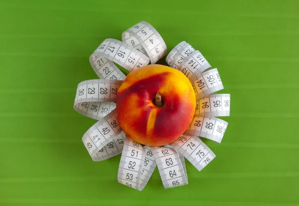 Peach and tape measure on the green background — Stock Photo, Image