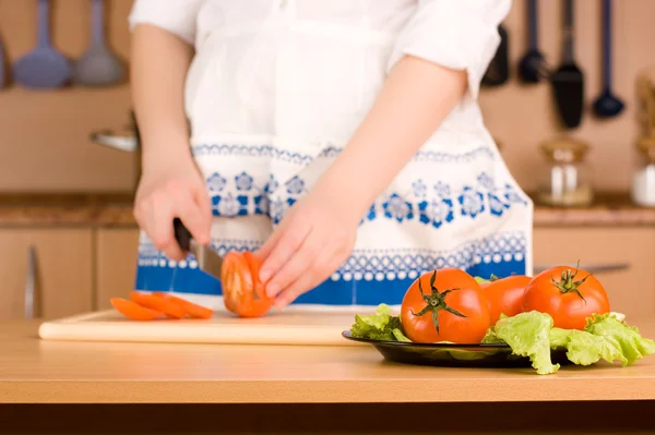 Kvinnans händer skära tomat (fokus på tallrik med tomater) — Stockfoto