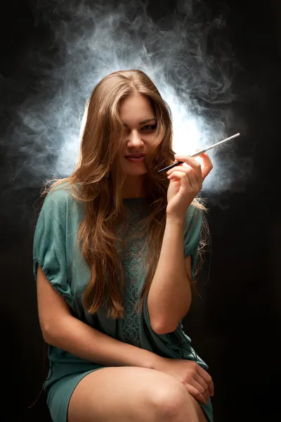 Belle femme aux lèvres pleines assise et fumant — Photo