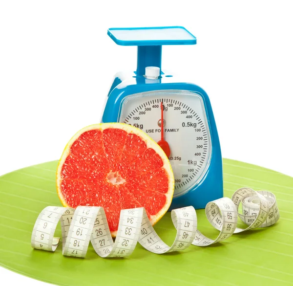A piece of grapefruit, measure tape and scale — Stock Photo, Image