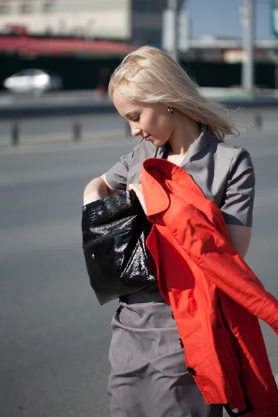 Женщина ходит и смотрит на свою сумочку — стоковое фото