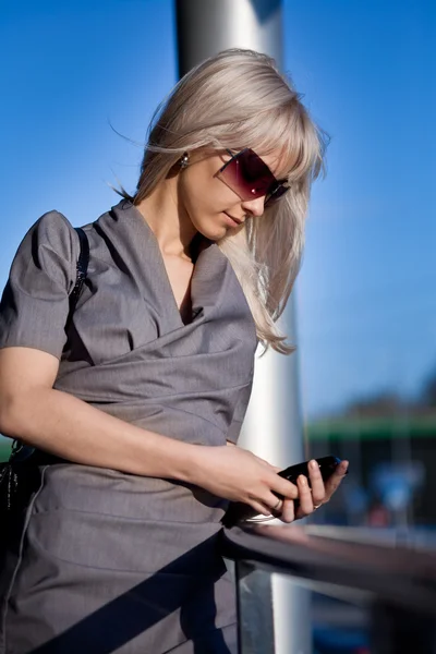 Mooie vrouw in zonnebril met cellphone wandelen — Stockfoto