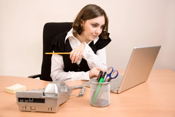 Joven secretaria con teléfono, ordenador portátil y pensamiento a lápiz —  Fotos de Stock