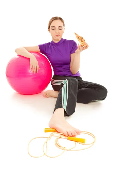 Mujer con una rebanada de pizza, pelota de gimnasia rosa y cuerda de salto — Foto de Stock