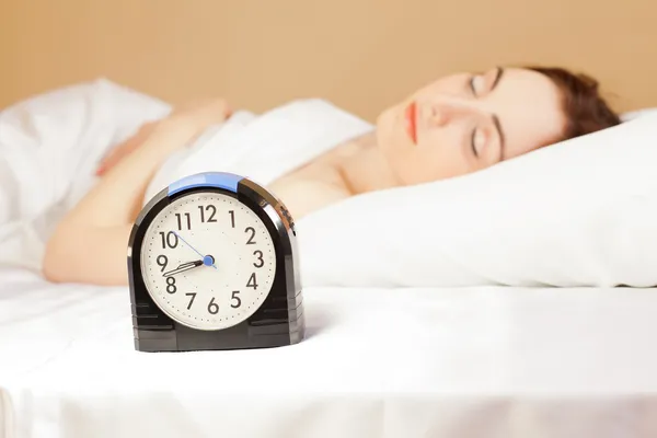 Kvinna som sover i sängen (fokus på väckarklocka) — Stockfoto