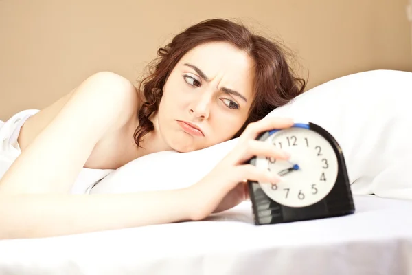 Mujer acostada en una cama y con una alarma (concéntrate en la mujer ) —  Fotos de Stock