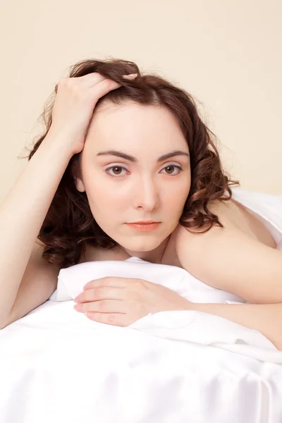 Piękna kobieta, leżąc na łóżku i patrząc na kamery — Zdjęcie stockowe