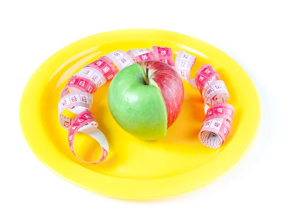 Yellow plate with mixed apple and tape measure — Stock Photo, Image