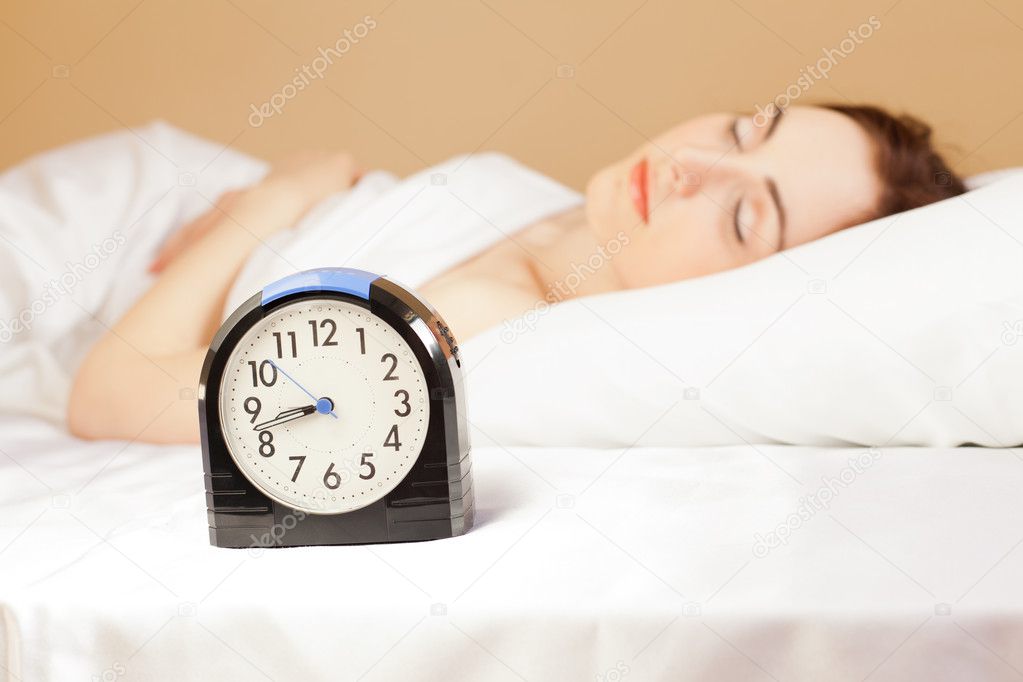 Woman sleeping in bed (focus on alarm clock)