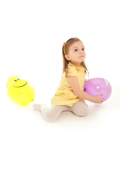 Grappig meisje, zittend op de vloer en spelen naar ballon — Stockfoto