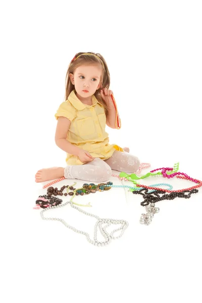 Displeased little girl with jewel sitting on the floor — Stock Photo, Image