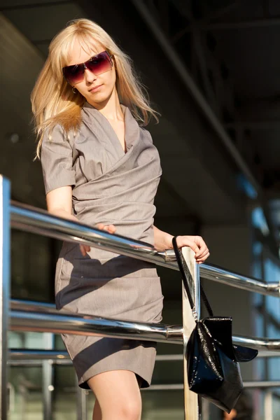 Žena v šedé šaty poblíž obchod — Stock fotografie