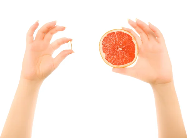 Woman's hands with piece of grapefruit and capsule — Stock Photo, Image