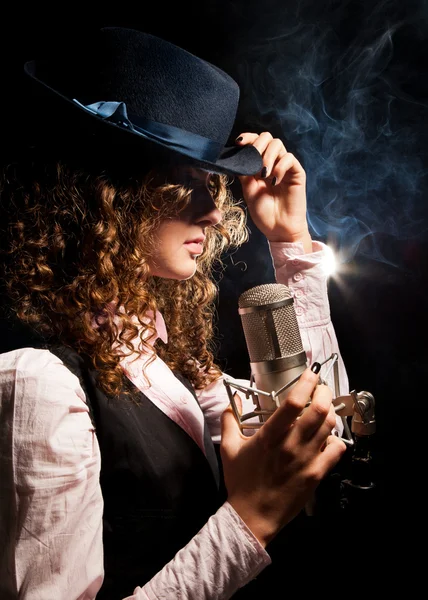 Mooie zanger in hoed met microfoon — Stockfoto