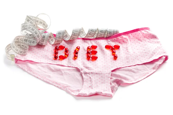 Inscription pills made on the pink panties with tape measure — Stock Photo, Image
