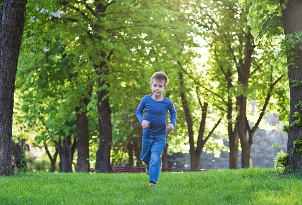 Šťastný malý kluk raning na trávě — Stock fotografie