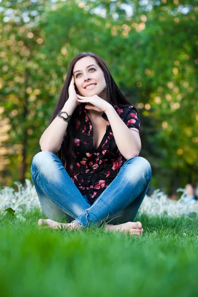 Счастливая симпатичная девушка, сидящая на траве — стоковое фото