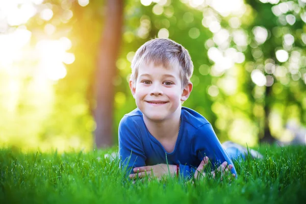 Смішний маленький хлопчик лежить на траві — стокове фото