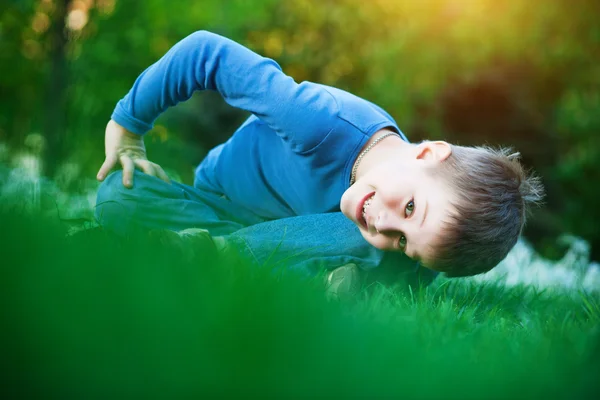 Щасливий маленький хлопчик лежить на траві — стокове фото