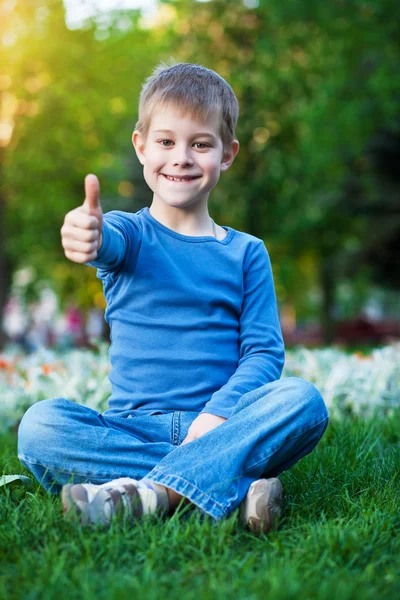 Criança alegre sentada na grama — Fotografia de Stock