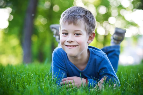 Усміхнений маленький хлопчик лежить на траві — стокове фото