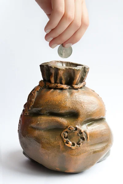 Χέρι εισάγει ένα κέρμα στην Τράπεζα γουρουνάκι — Φωτογραφία Αρχείου