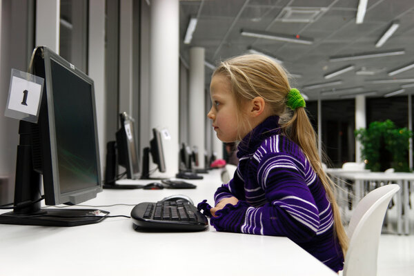 Маленькая девочка пользуется компьютером в библиотеке
